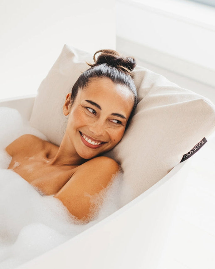 Perlmutt Badesofa Rückenkissen (Size Large) in einer freistehenden Badewanne, mit lächelnder Person, die sich entspannt anlehnt. $ Freistehende Badewanne | Size Large | Perlmutt